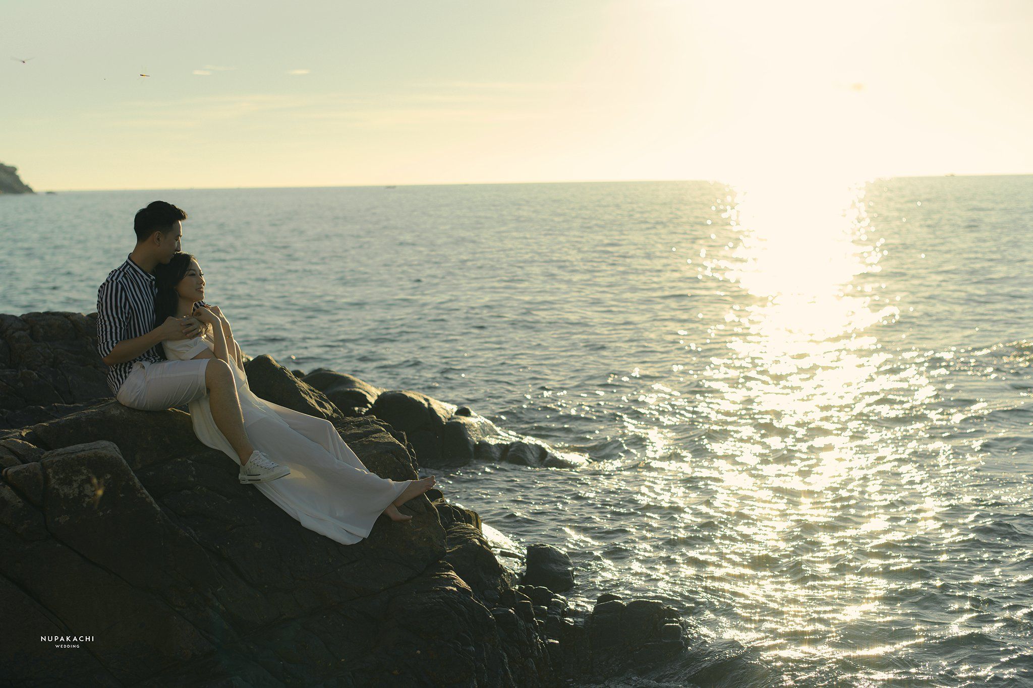 Couple watching the sunset over the sea during a destination pre-wedding session in Vietnam