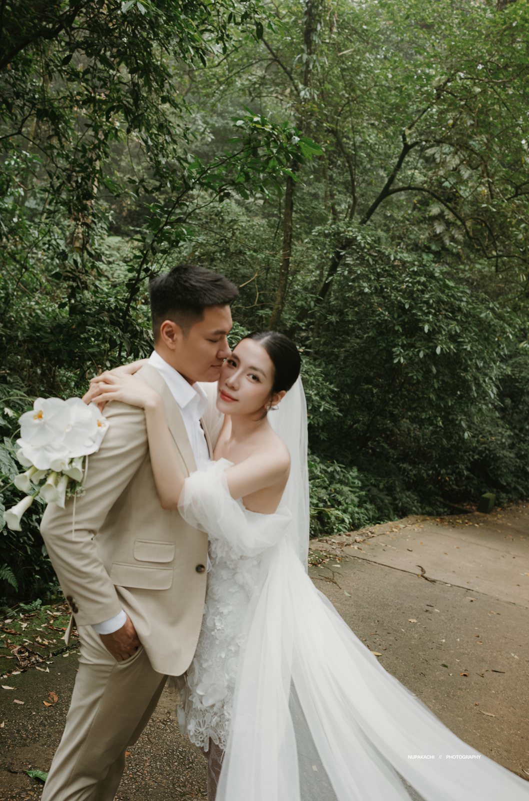 Cô dâu ôm chú rể với bó hoa trắng giữa rừng Ba Vì