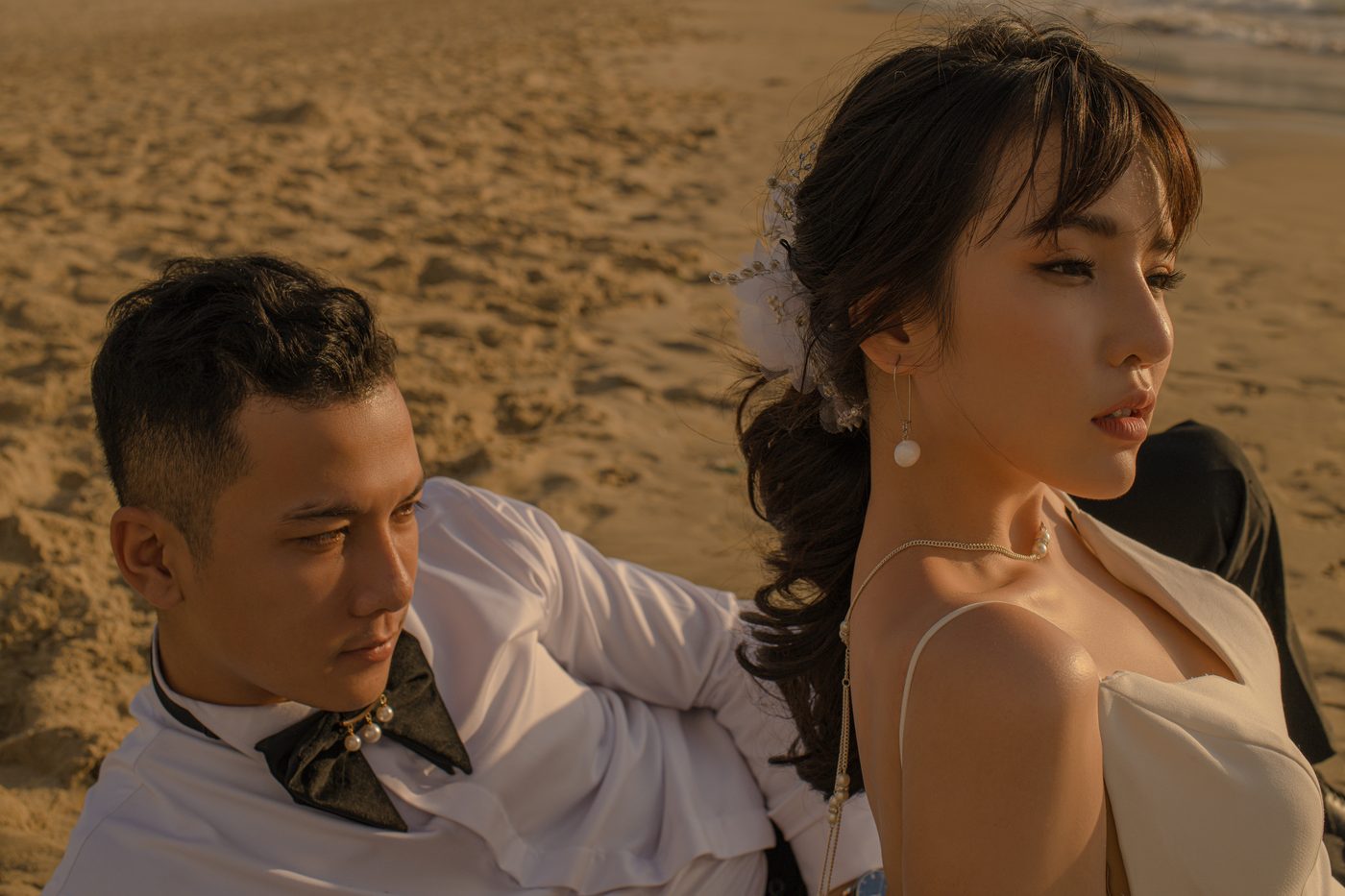 Cặp đôi ngồi trên cát nhìn nhau lúc chiều xuống, chụp ảnh cưới Đà Nẵng