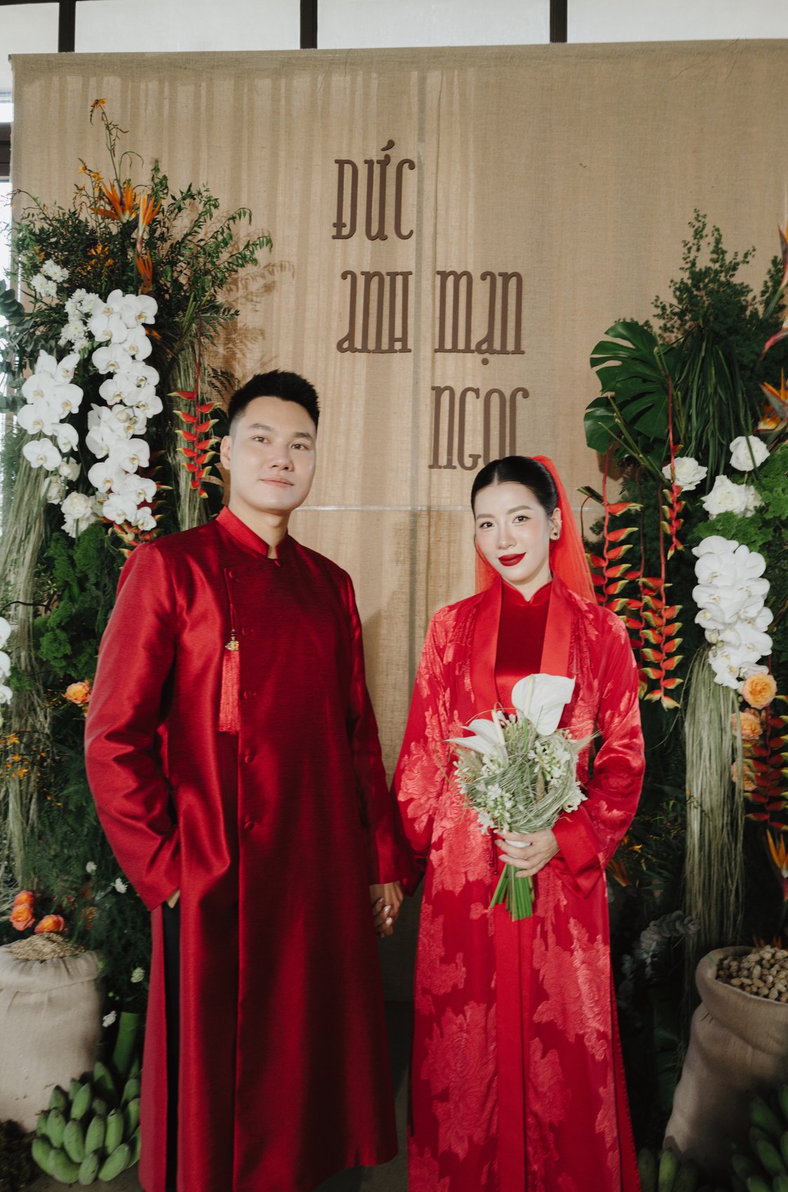 Couple in red at their name backdrop during a destination wedding party, Vietnam