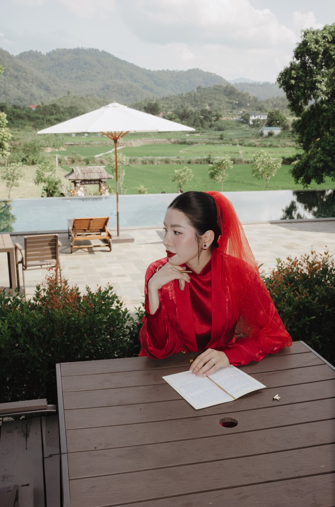 Bride in red writing her vows overlooking the rice fields before the ceremony, destination wedding Vietnam