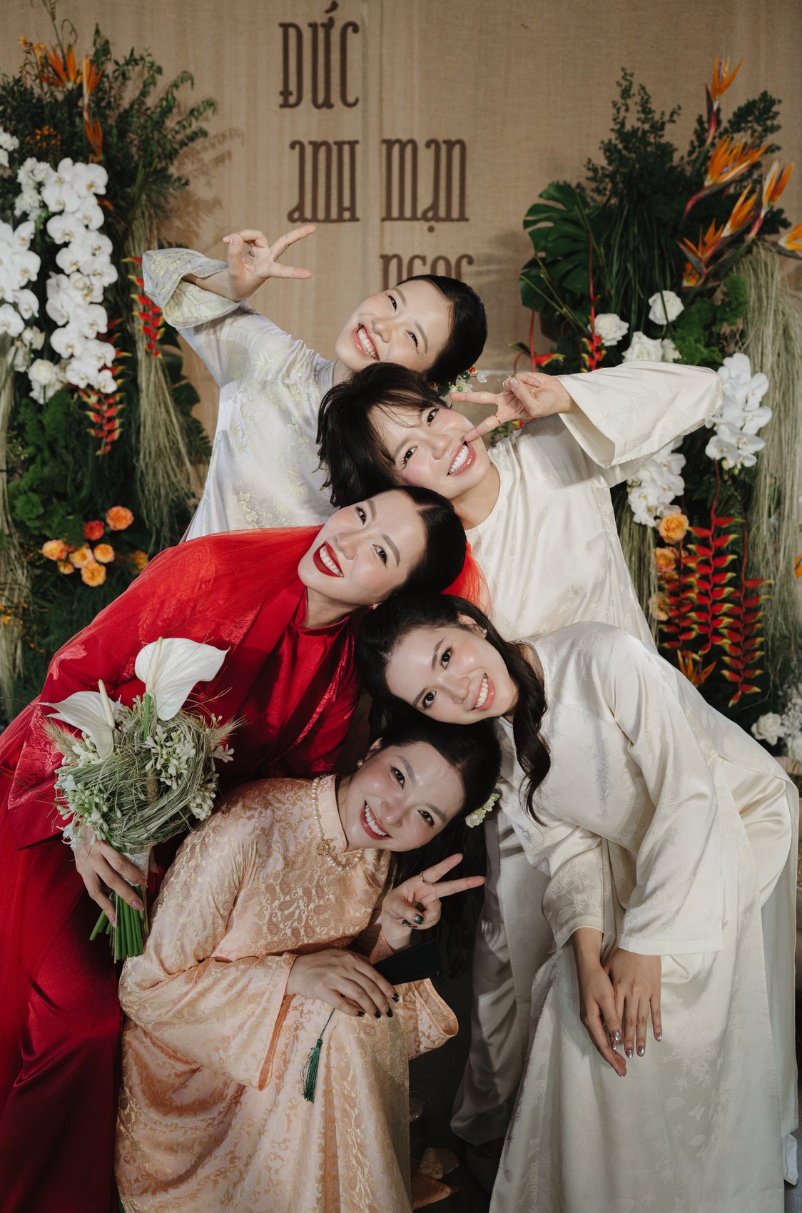 Bride hugging her bridesmaids with bouquets at a countryside wedding, Vietnam