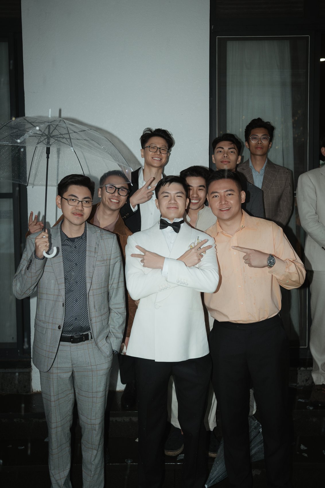 Groomsmen with umbrellas laughing at an outdoor destination wedding, Vietnam