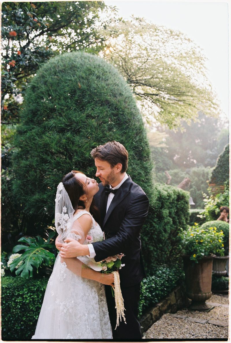 Bride and groom in a topiary garden and glasshouse on 35mm film (frame 3 of 12)