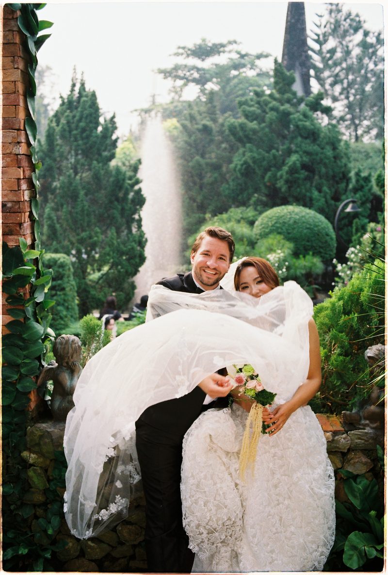 Bride and groom in a topiary garden and glasshouse on 35mm film (frame 6 of 12)