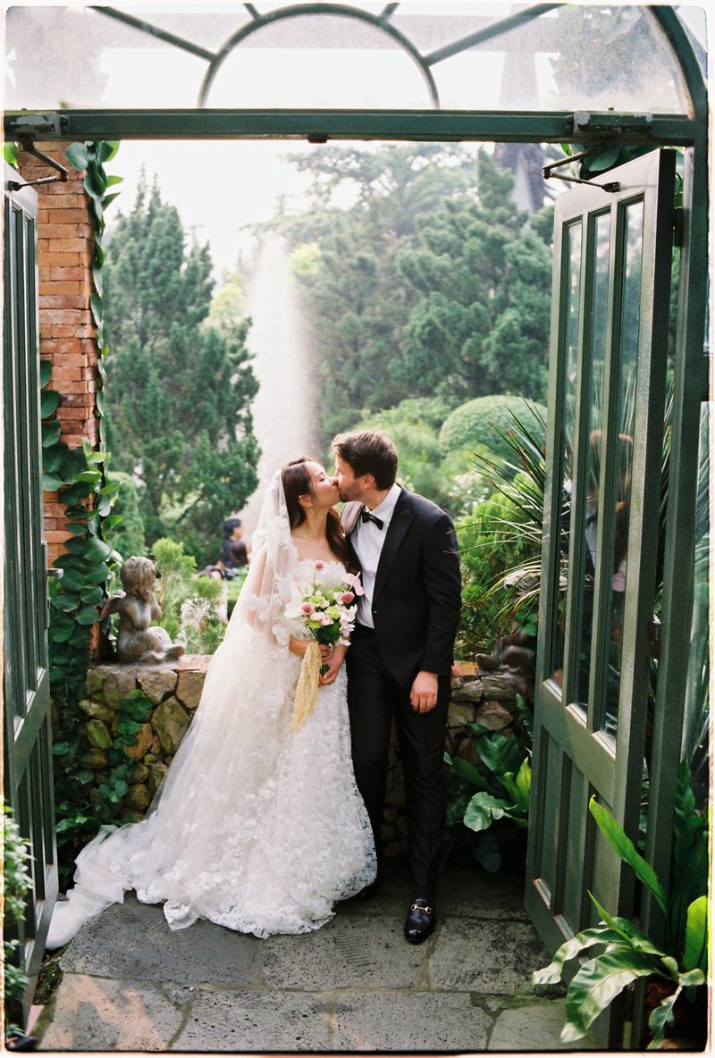 Bride and groom in a topiary garden and glasshouse on 35mm film (frame 7 of 12)