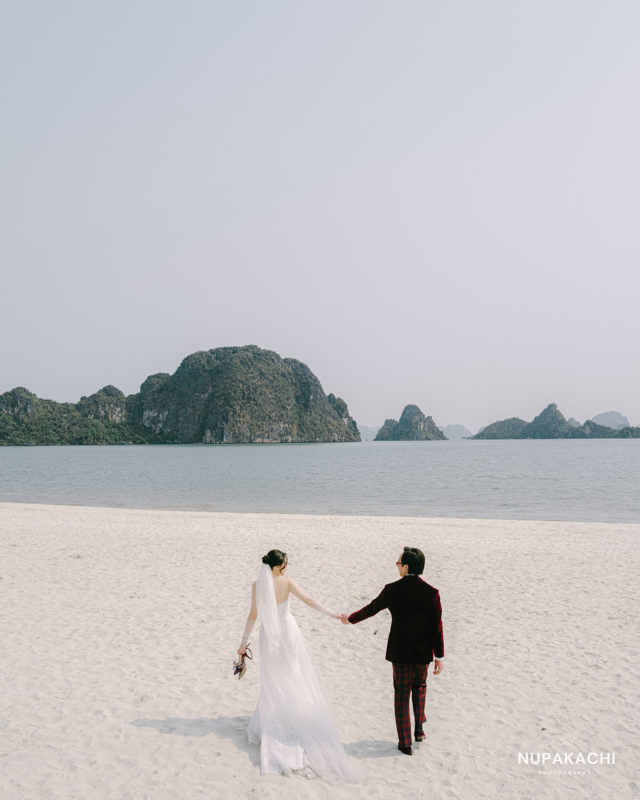 Cô dâu chú rể nắm tay chạy trên bãi biển Quảng Ninh