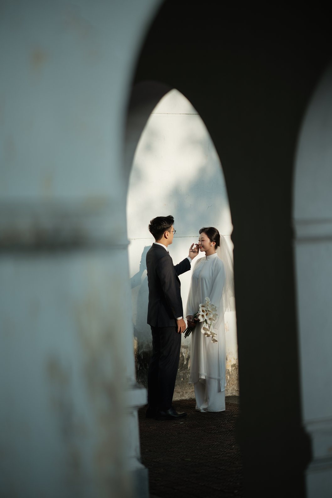 Cô dâu trong tà áo dài trắng dưới vòm cửa cổ, chụp ảnh cưới Hoàng Thành