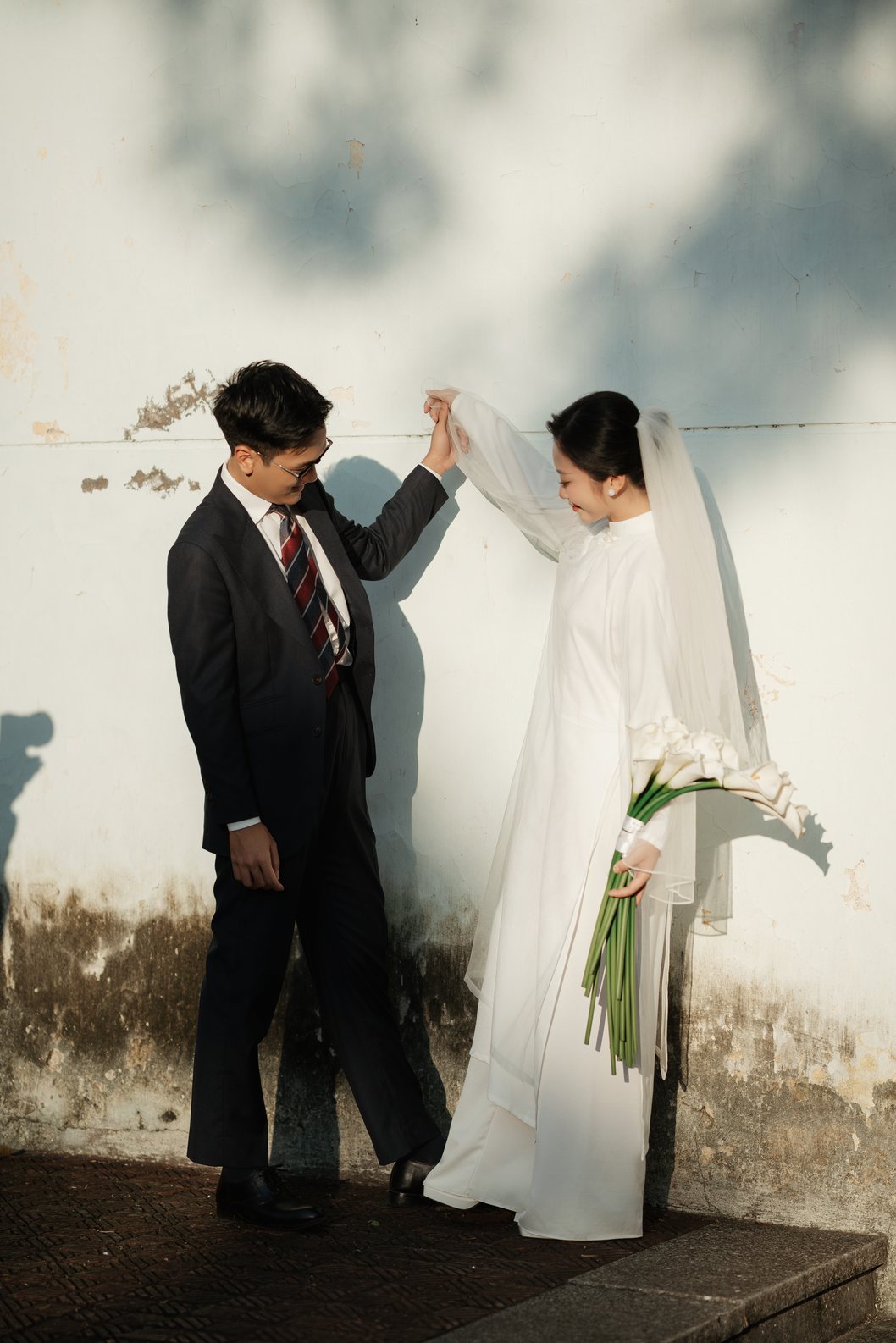 Chú rể nâng tay cô dâu bên tường vôi cũ, prewedding Hà Nội