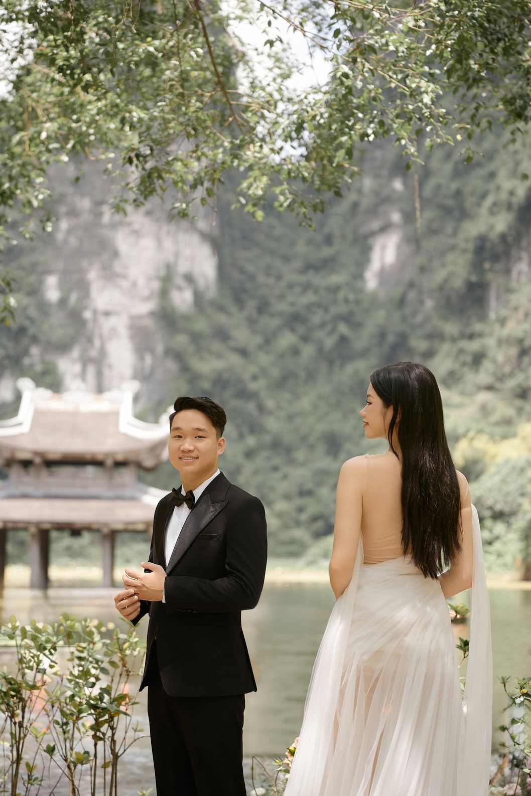 Cô dâu chú rể bên hồ, sau lưng là thủy đình và vách núi Tràng An