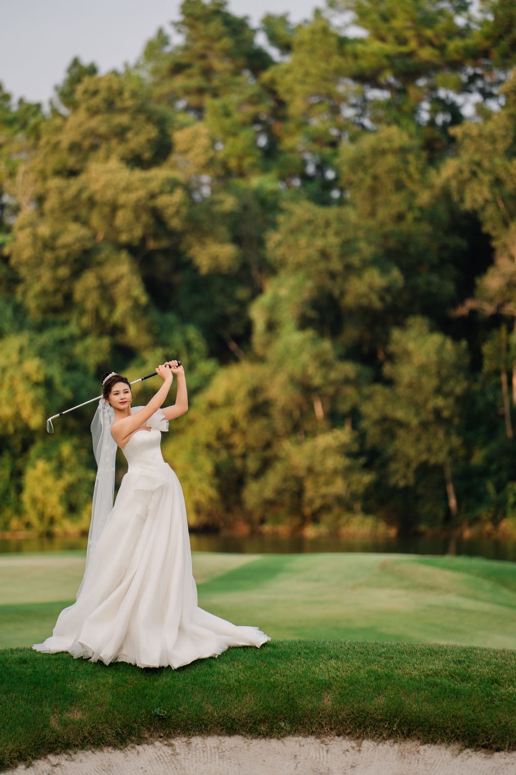 Cô dâu vung gậy golf bên hồ trong nắng chiều, sân golf Tràng An