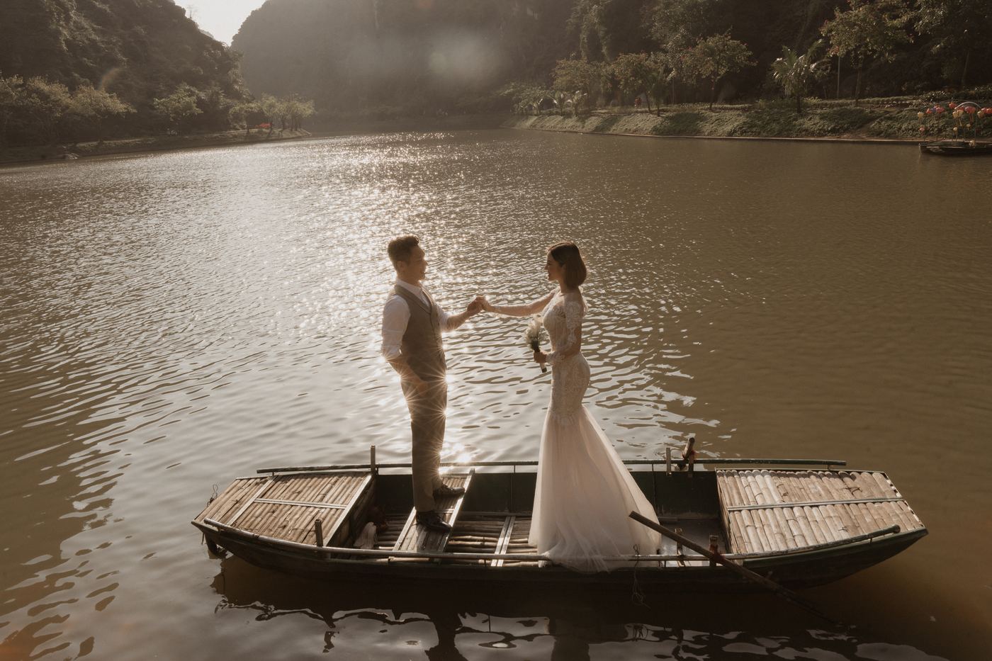 Cặp đôi đứng trên thuyền nan giữa sông trong nắng chiều Tràng An
