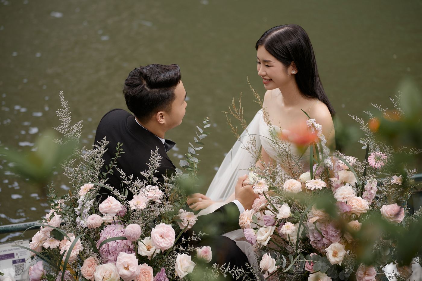 Chú rể và cô dâu cười với nhau trên thuyền hoa, chụp ảnh cưới Tràng An