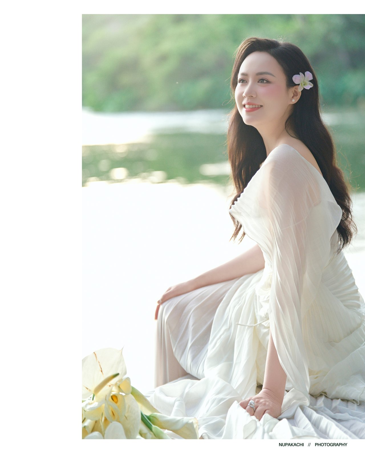 Bride seated lakeside in white gown, minimalist pre-wedding portrait Vietnam
