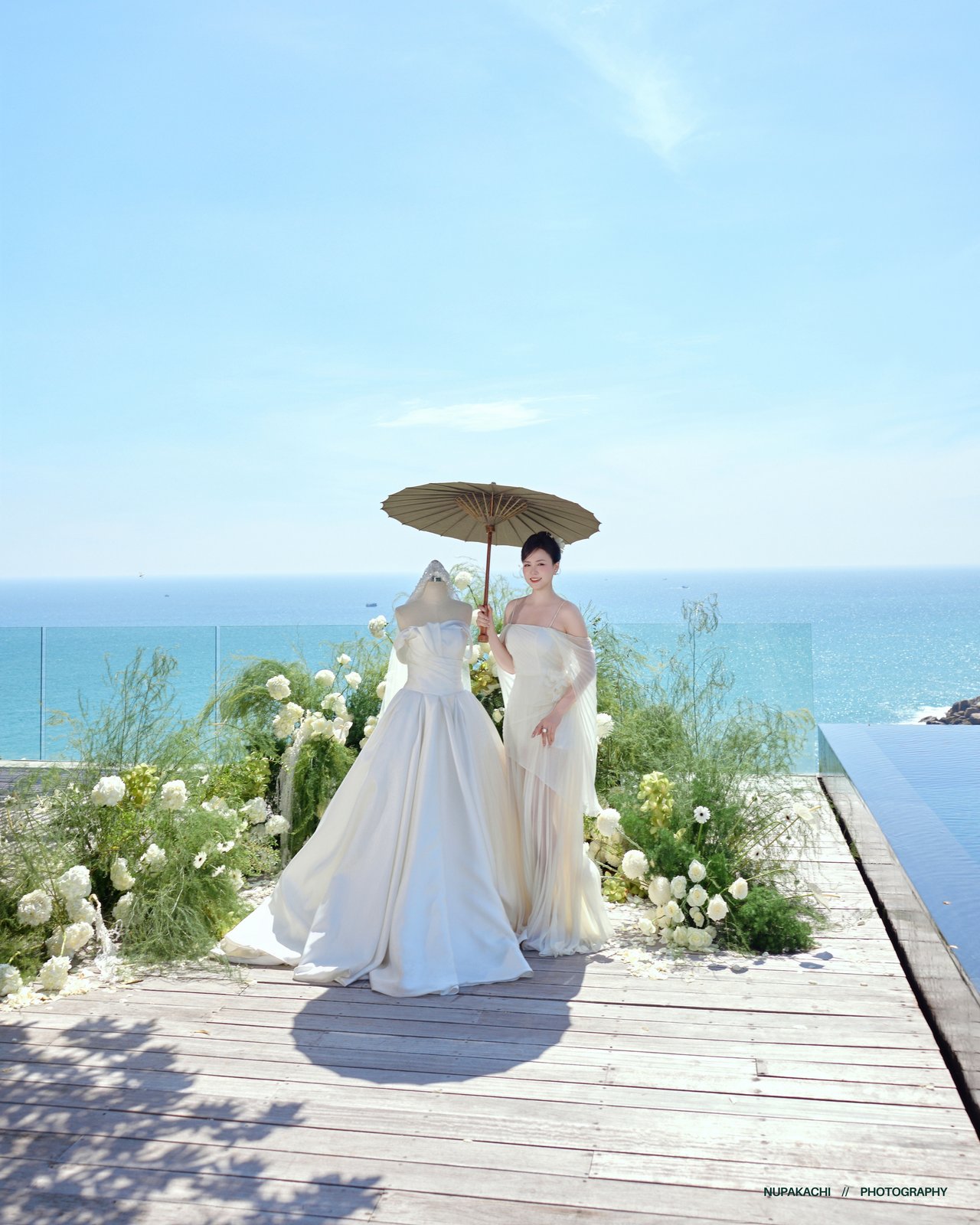 Couple under a white umbrella on a wooden deck over the sea, Amanoi Ninh Thuan