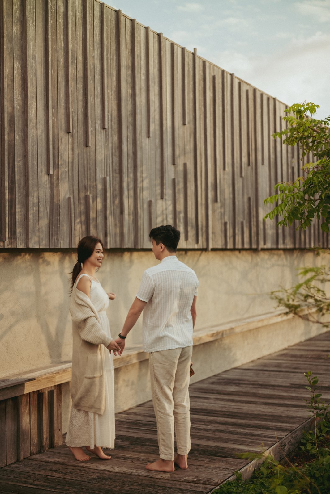 Casual linen outfits pre-wedding by a wooden wall, natural style Vietnam
