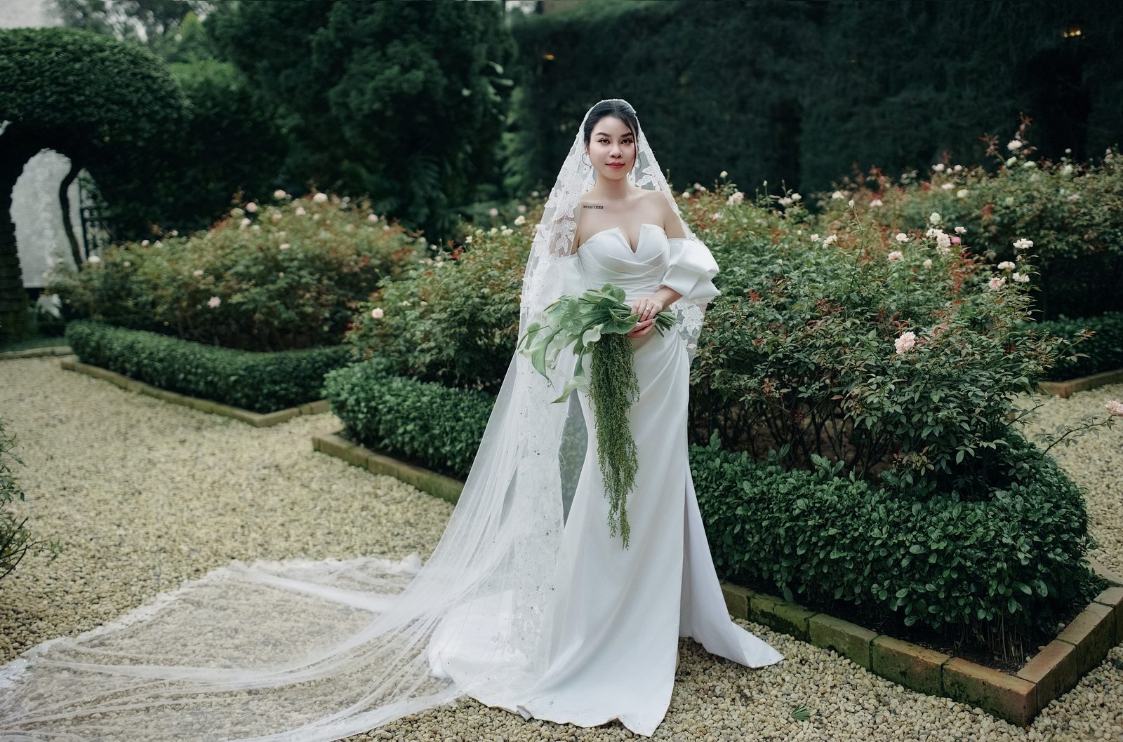 Linh in a silk gown with a long lace veil