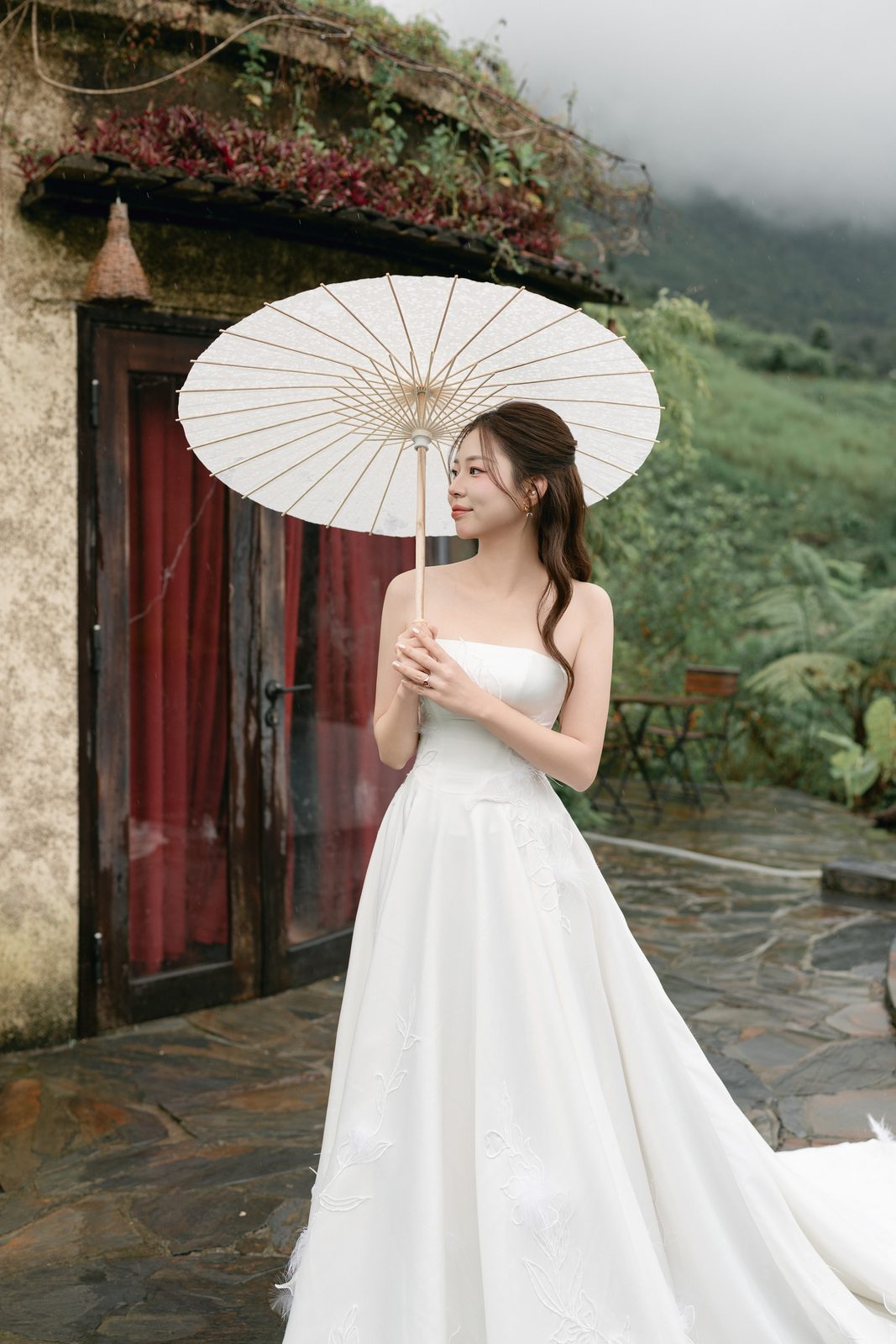 A paper parasol by a stone house with a grass roof