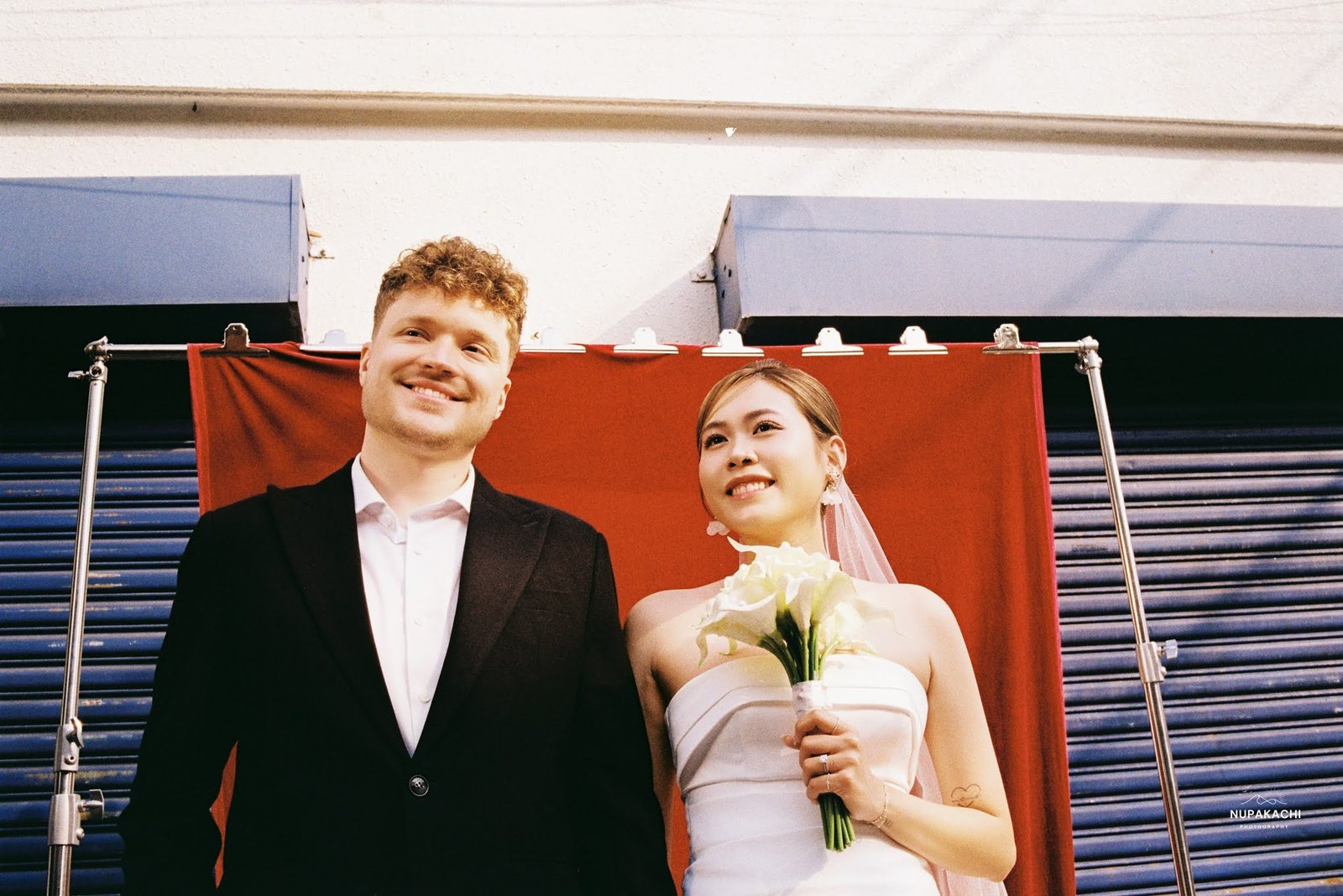 A red backdrop set up on the pavement against blue shutters
