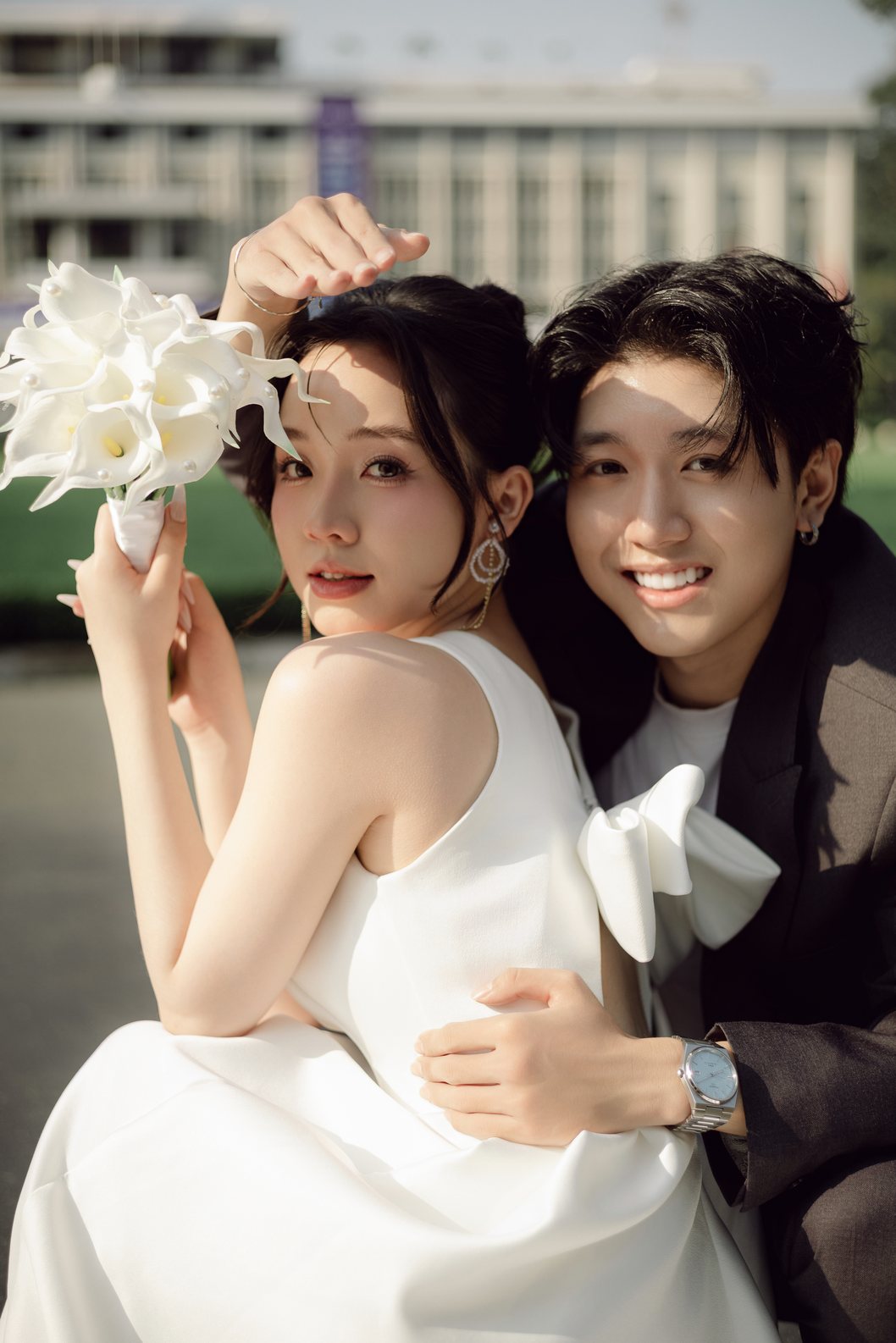 Chú rể ôm cô dâu cầm hoa trắng, chụp ảnh cưới Sài Gòn