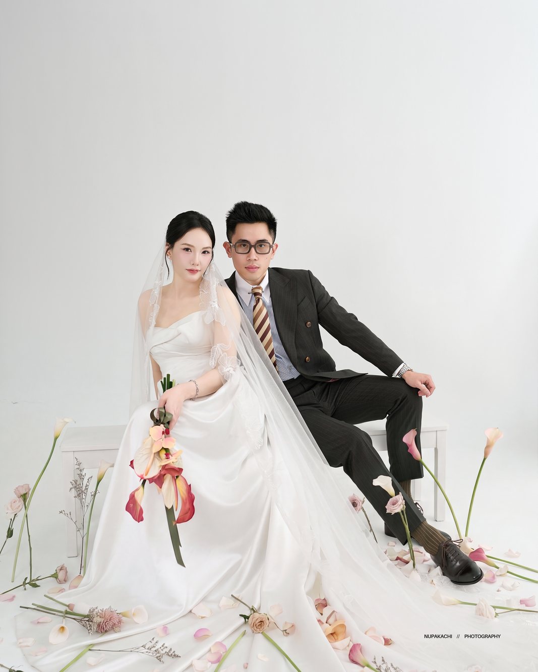 Bride and groom seated together in a bright studio with orchids, Nupakachi wedding