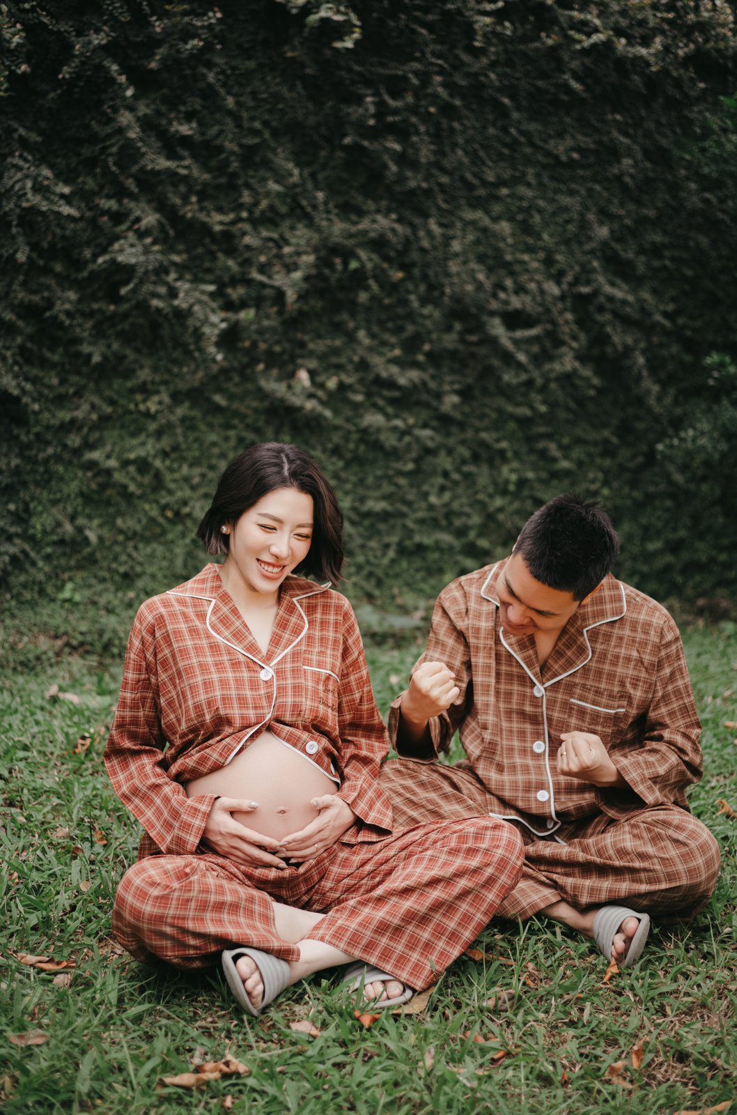 Couple in matching pajamas relaxing on the grass, lifestyle maternity session