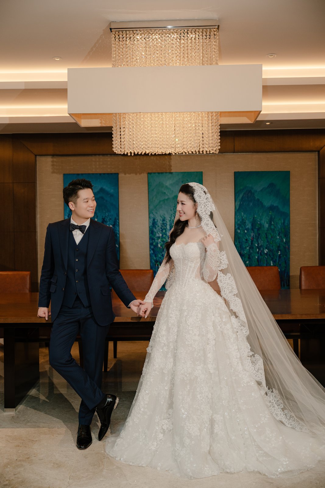 Bride and groom under chandeliers, documentary wedding day photography in a Vietnam ballroom