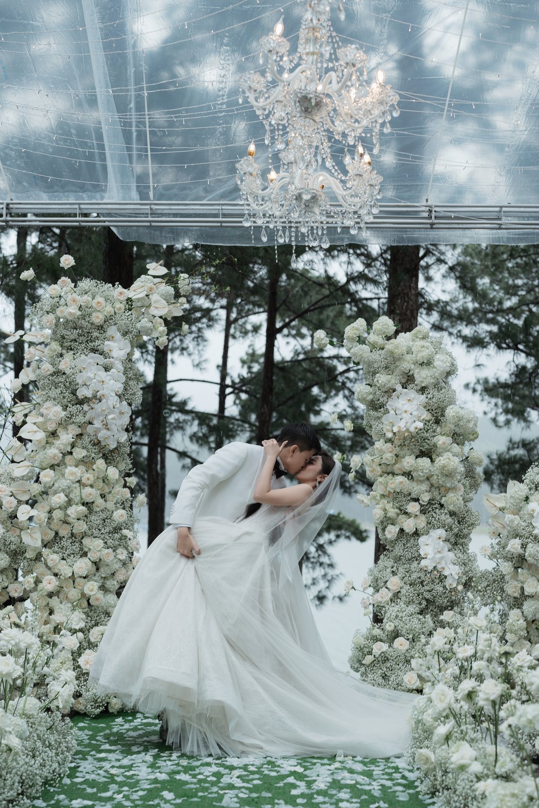 Bow of gratitude under chandeliers in a glasshouse wedding, Vietnam