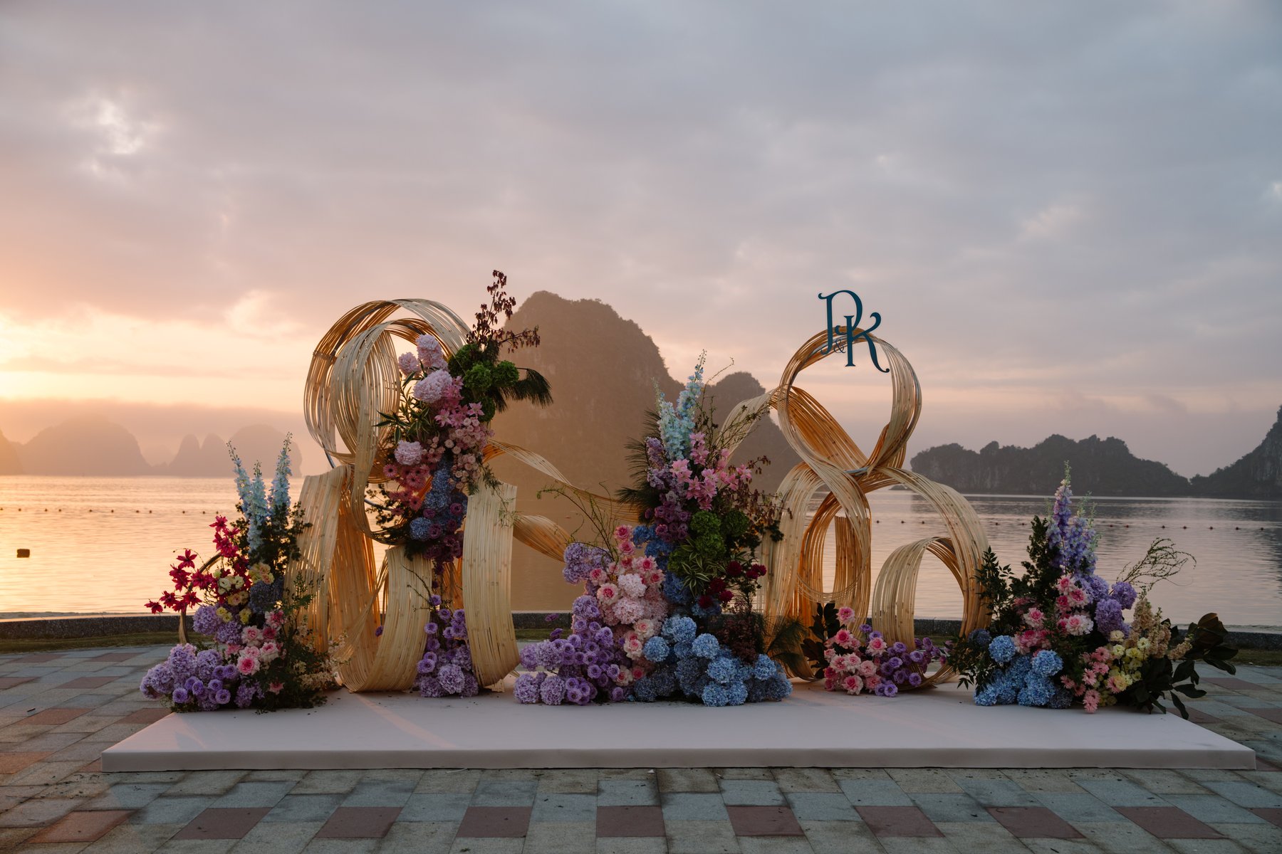 Sunset wedding backdrop by the bay with floral rings installation, Ha Long Vietnam
