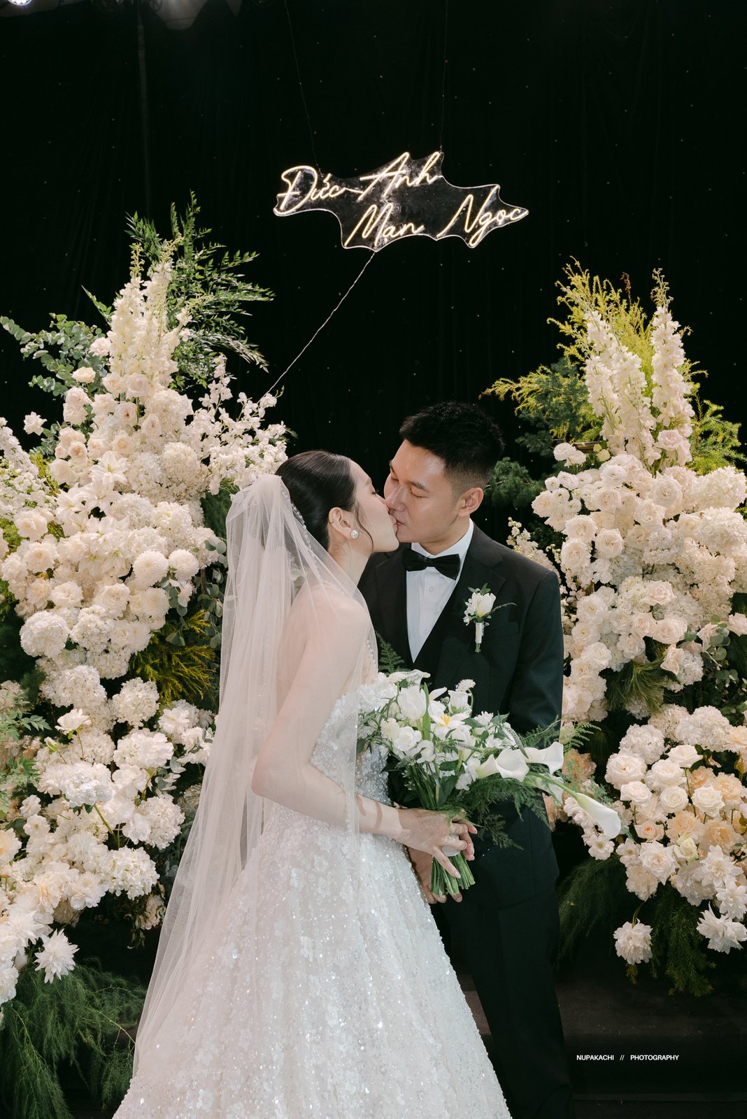 Couple kissing under neon sign at wedding party, candid celebration Vietnam