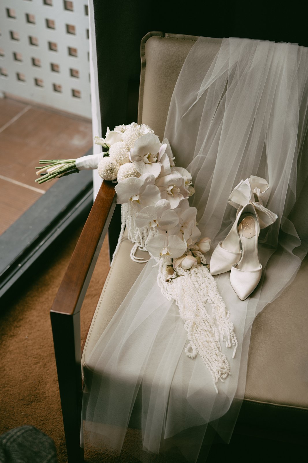 Bridal accessories on a chair: bouquet, veil, pearls and heels, wedding morning details Vietnam