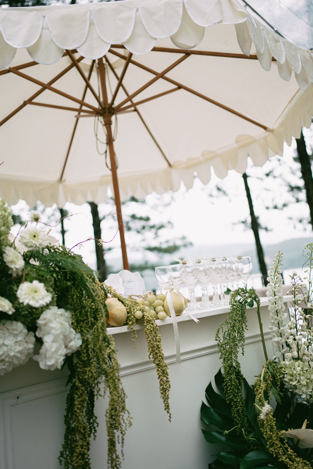 Fringed parasol over florals and fruit at an outdoor wedding, decor details Vietnam