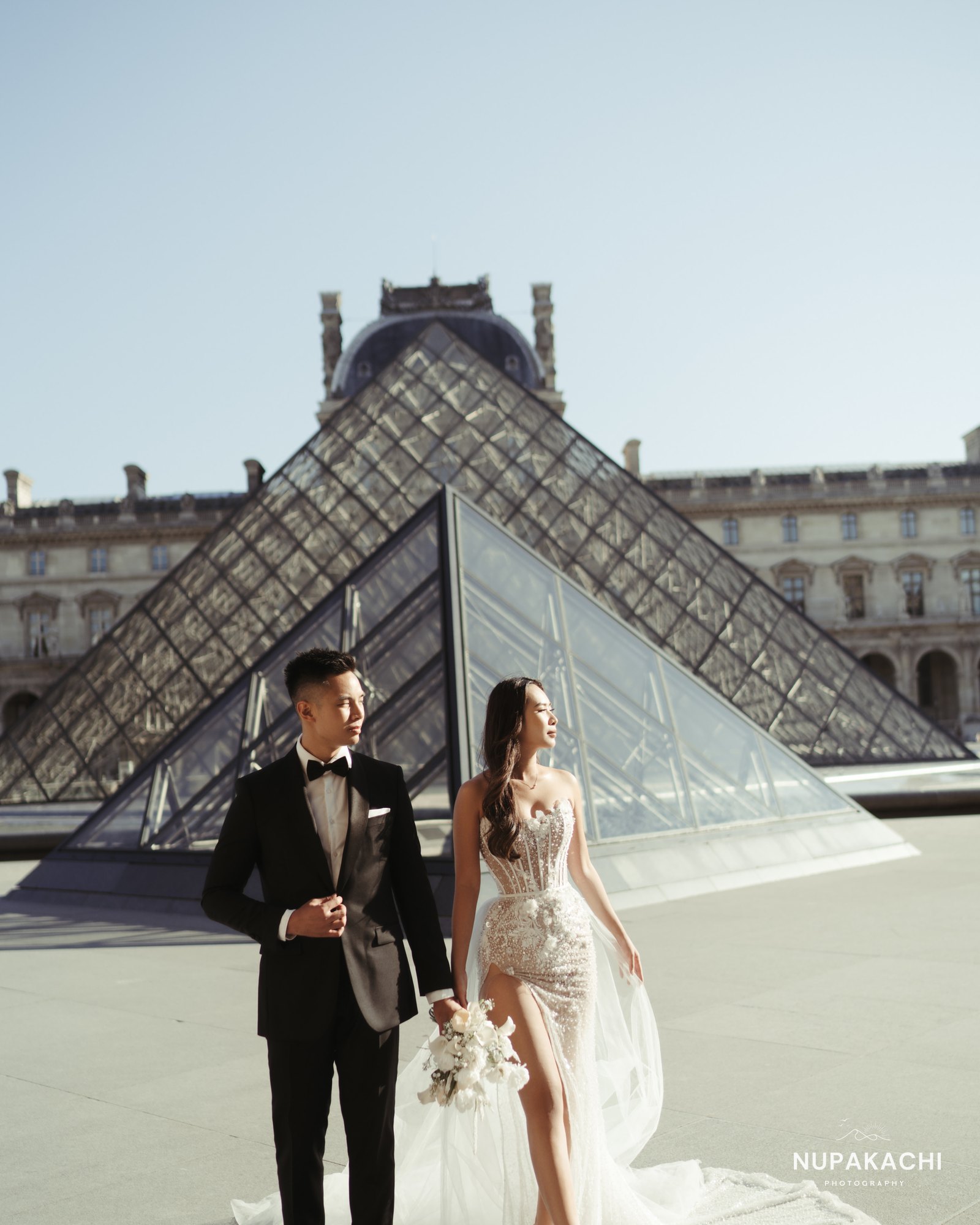 Groom and bride at the Louvre pyramid, Paris destination wedding photography