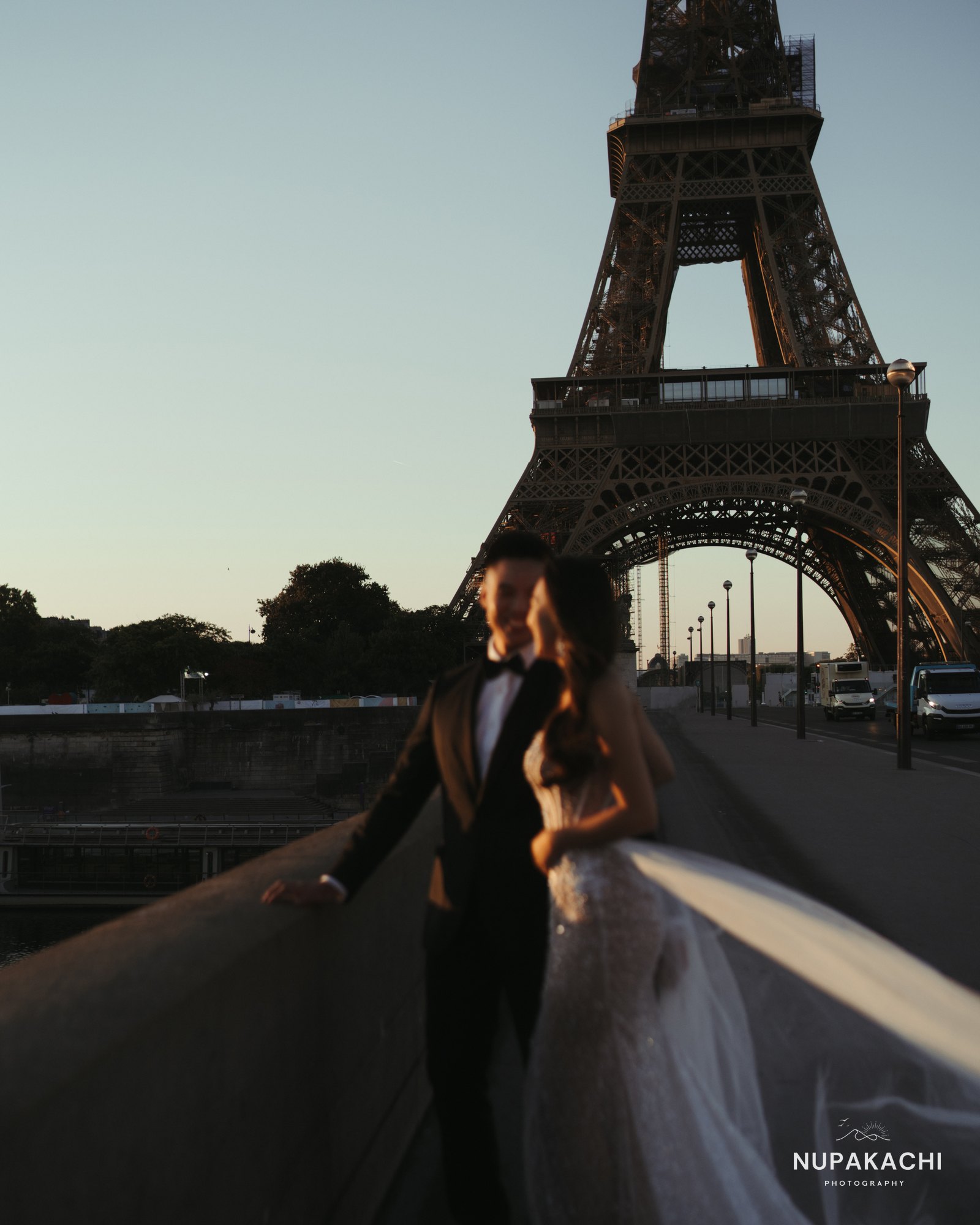 Couple with flowing veil on a Paris bridge at golden hour