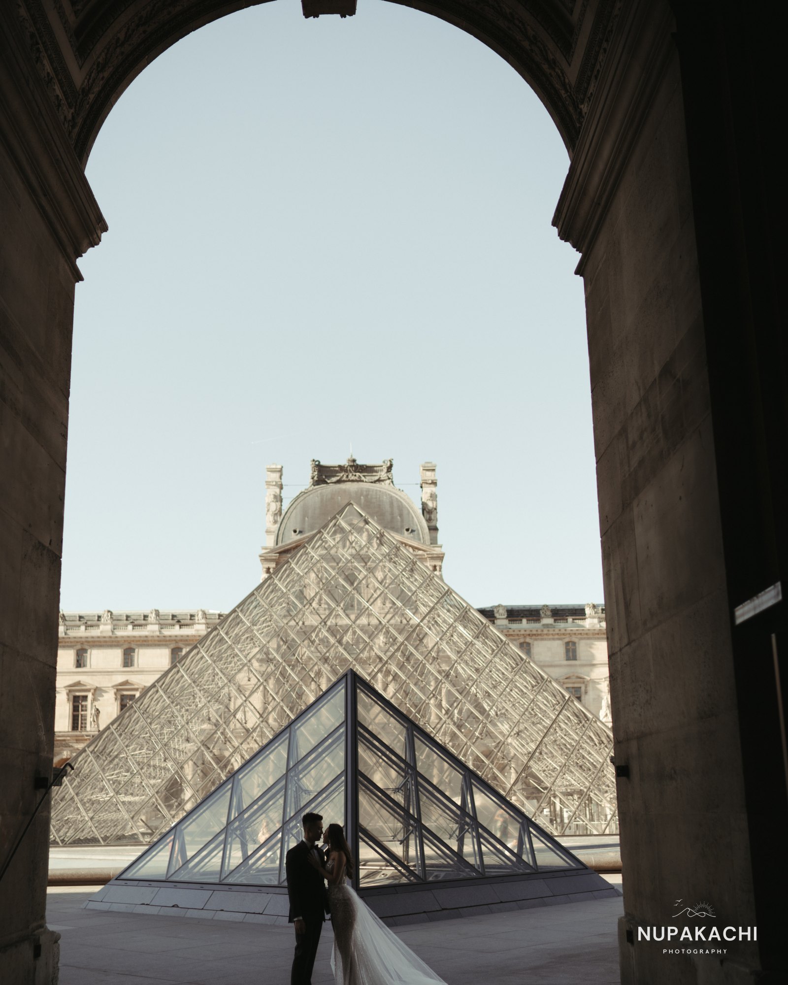 Couple under the Louvre archway, architectural Paris photography