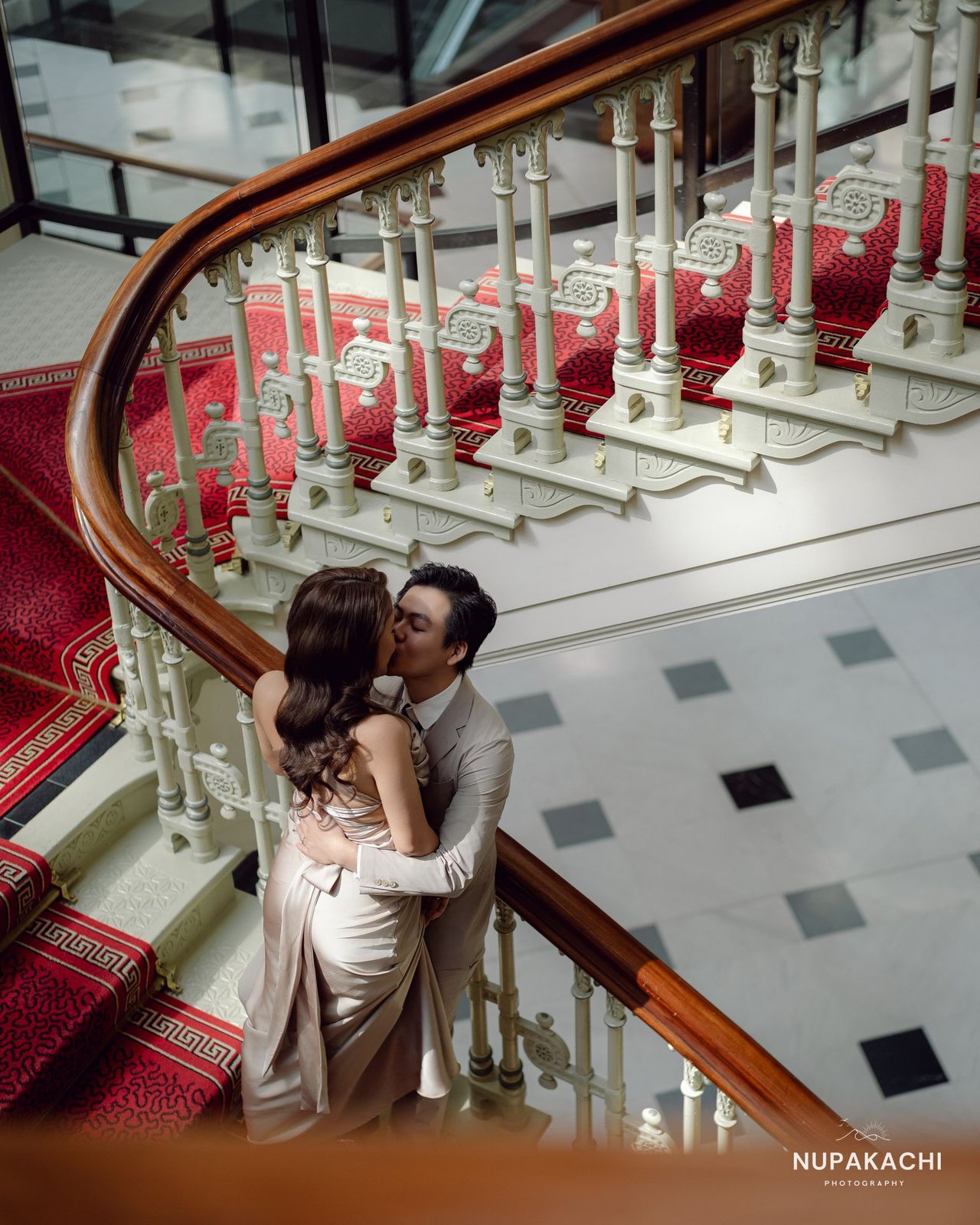 Grand staircase embrace in a Paris hotel, editorial wedding portrait