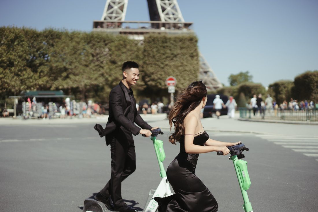 Hai người chạy xe điện trên phố Paris