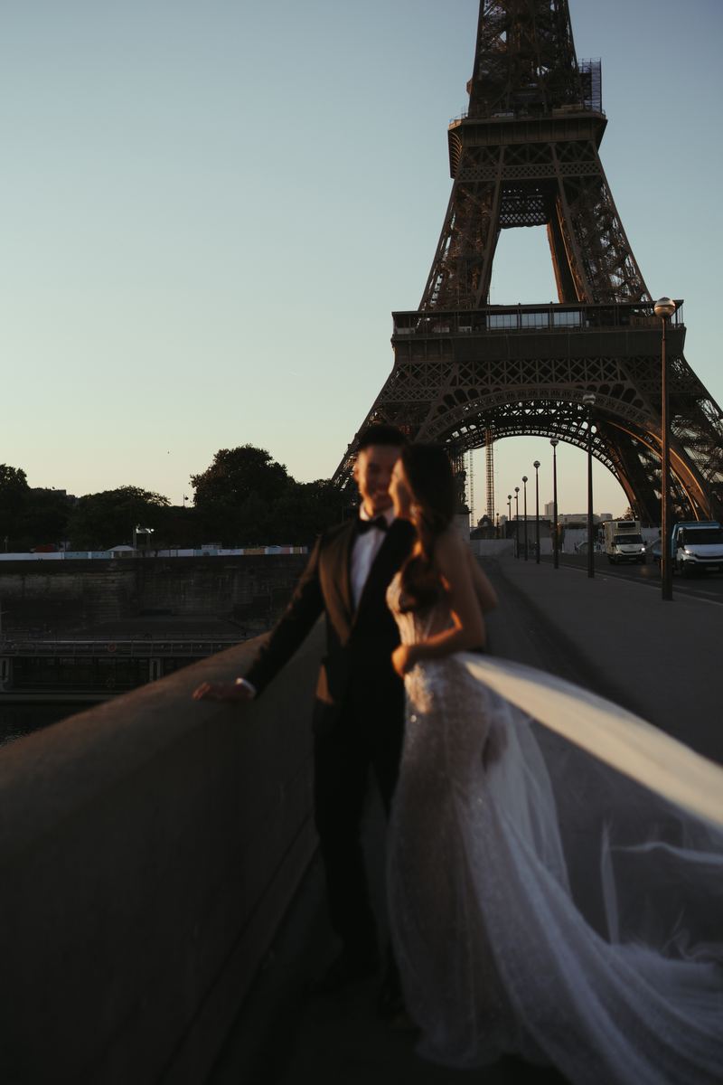 Cặp đôi đi bộ trên phố Paris trong bộ vest trắng
